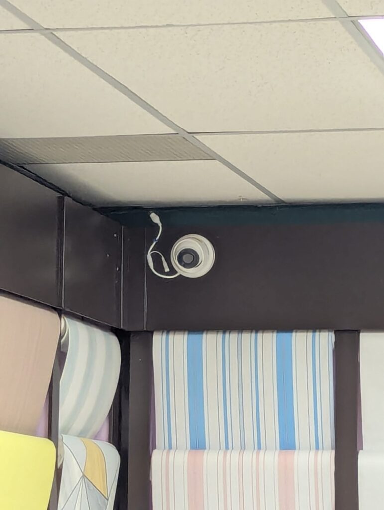 White dome security camera ceiling-mounted in a business showroom